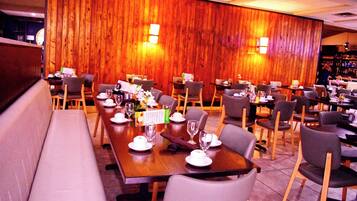 A restaurant with wooden panel walls, multiple dining tables, and chairs.