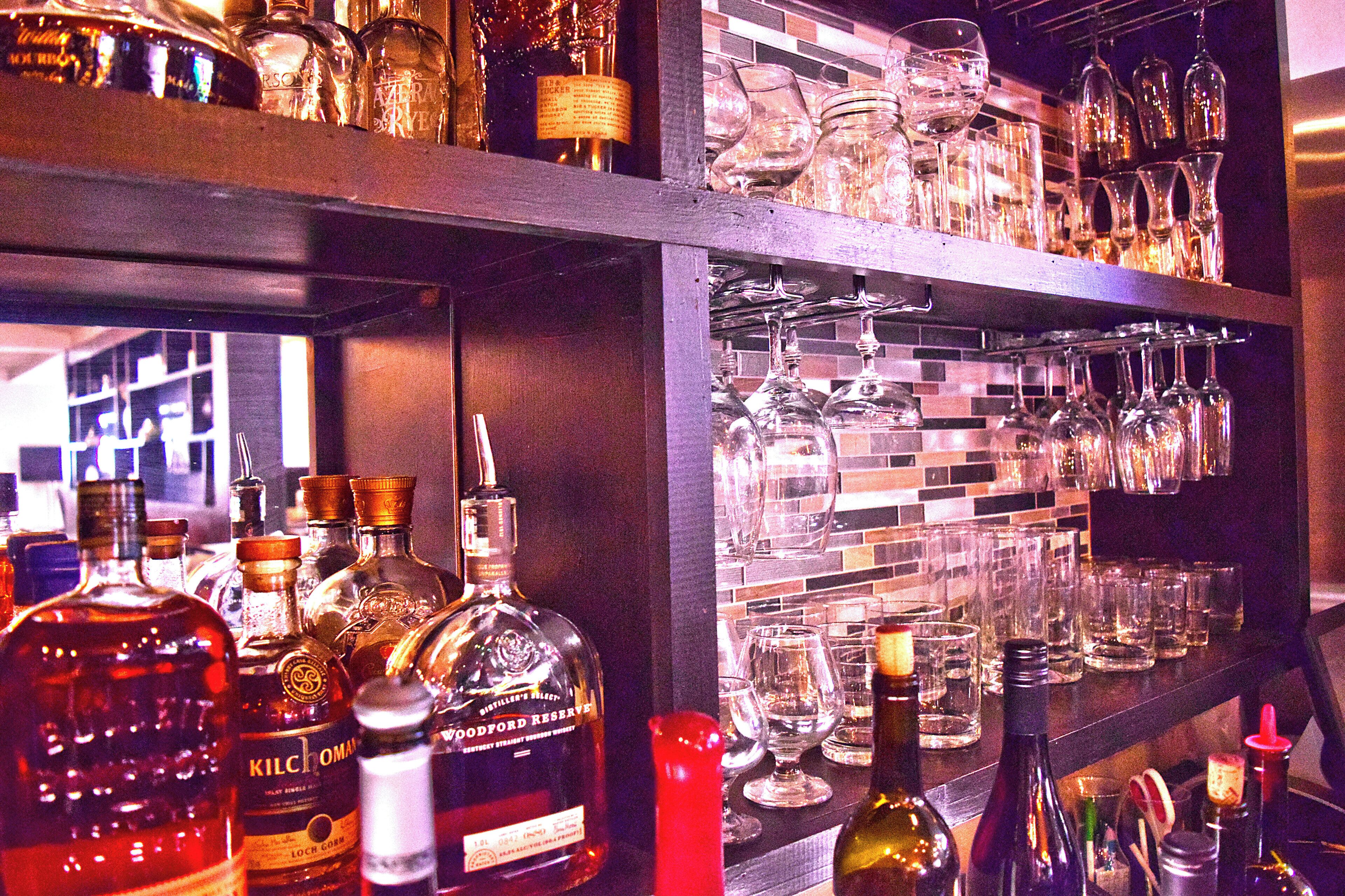 A bar area with shelves stocked with liquor bottles and glasses.