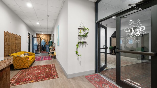 Een moderne hotel lobby met een houten scheidingswand, een gele bank en een rood tapijt met een patroon.