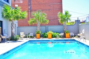 Piscina cercada por cadeiras e plantas em vasos.