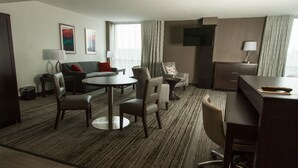 Een hotelkamer met een eethoek, een bank, een televisie en een lamp.