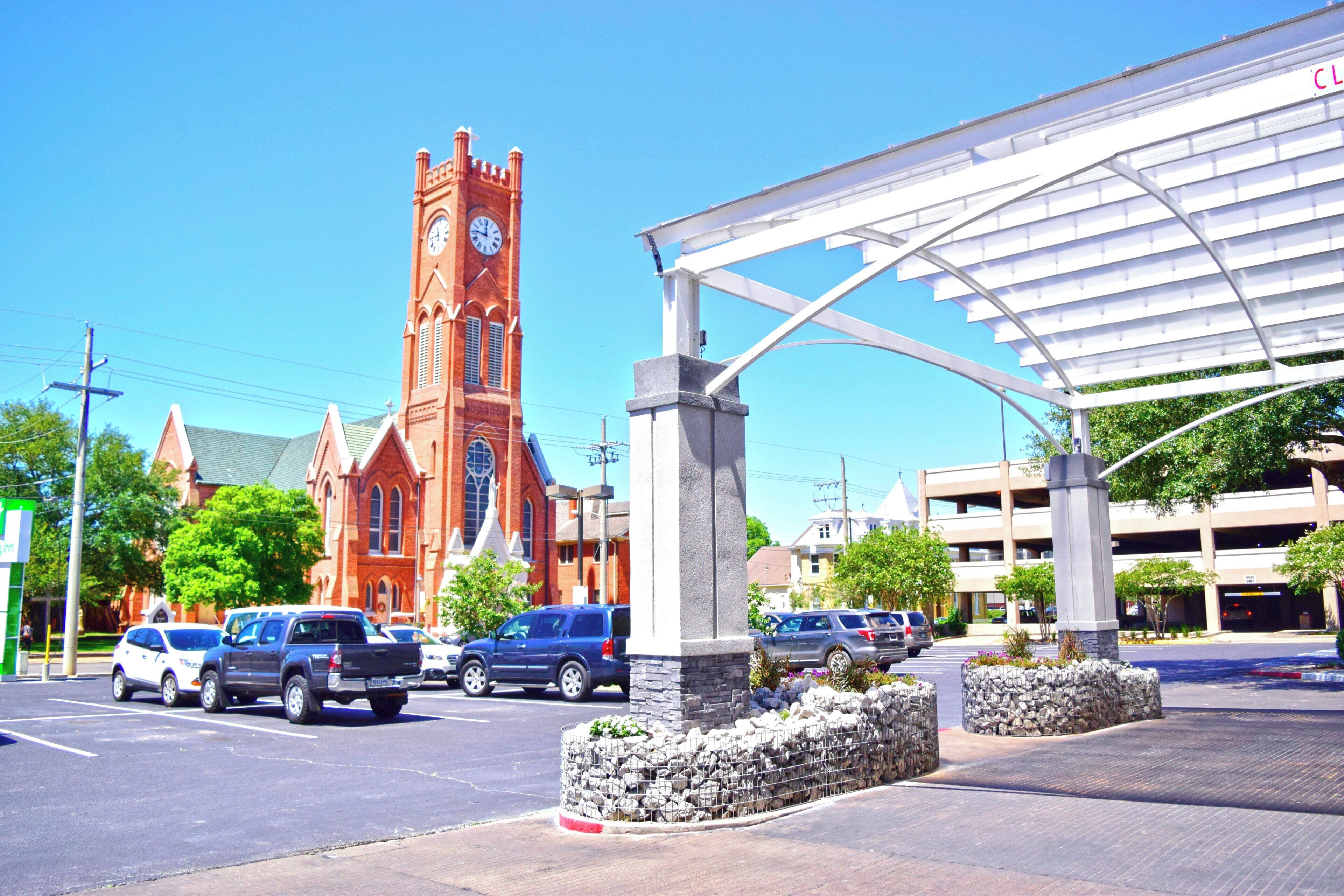 A parking area with a stone wall and a covered walkway.