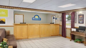 A reception area with a wooden counter, a clock, and a computer on a desk. - Days Inn by Wyndham Lake City I-75 (Lake City)