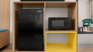 A kitchen with a black refrigerator and a microwave on a wooden shelf. - Days Inn by Wyndham Lake City I-75 (Lake City)