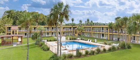A hotel with a swimming pool, multiple balconies, and lush greenery.