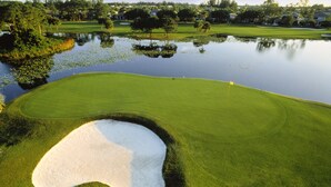 Un campo de golf con un búnker de arena, obstáculos de agua y un marcador de bandera.