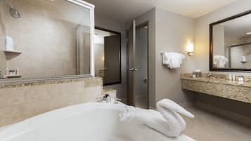 A modern bathroom with a large bathtub, a vanity with a granite countertop, and a mirror above the sink.