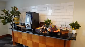 En buffé med ett varierat utbud av mat, en dryckesdispenser och dekorativa växter.