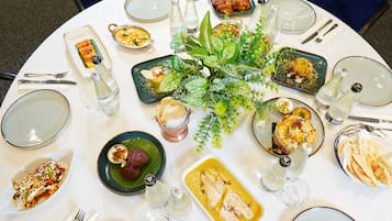 Una mesa redonda de comedor con diversos platos, utensilios y plantas decorativas.