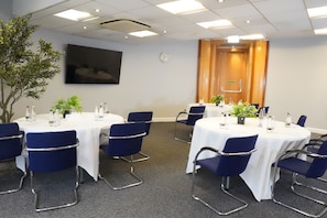 A conference room with round tables, blue chairs, and potted plants. - Best Western Heathrow Ariel T2, 3, 4 (Hayes)