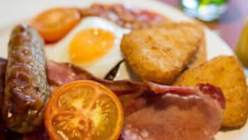 A plate of breakfast food including sausages, eggs, bacon, and toast.