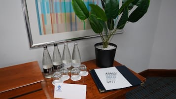 A wooden desk with a potted plant, three bottles of Harrogate sparkling water, and a notebook with pens.