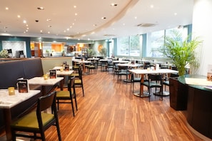 A spacious restaurant with multiple tables and chairs, a counter area, and large windows allowing natural light. - Best Western Heathrow Ariel T2, 3, 4 (Hayes)