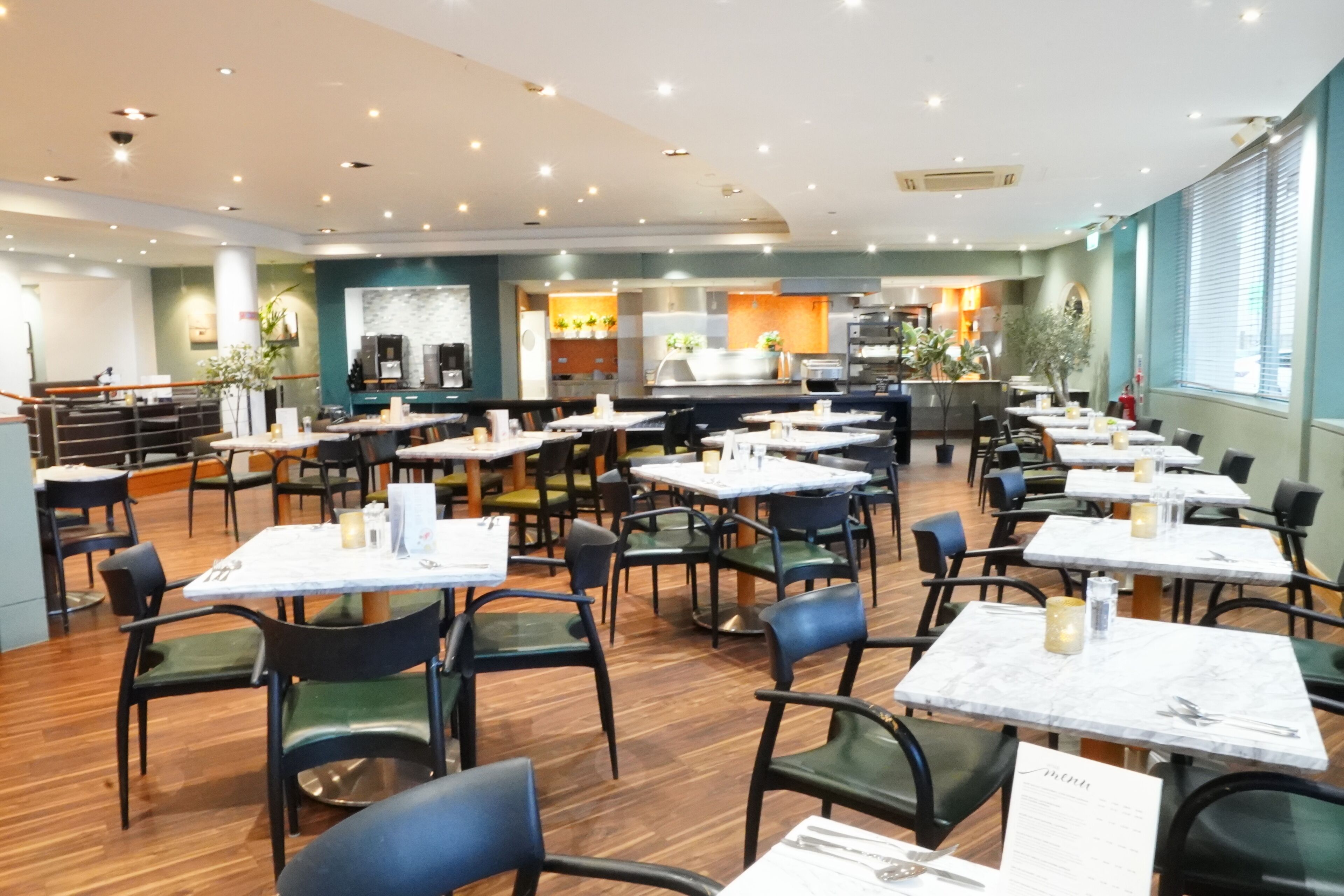Un restaurante con varias mesas y sillas, una zona de cocina y una barra.