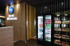 Vastaanottoalue, jossa on näkyvillä kyltti, jossa lukee ”Best Western”, puusäleistä tehty seinä ja juoma-automaatti, joka on täytetty erilaisilla juomilla.