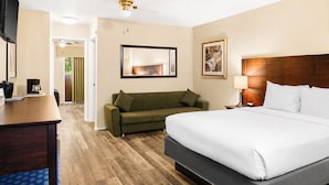 A hotel room with a bed, a desk, a sofa, and a mirror. - Scottish Fairway Inn (Monterey)