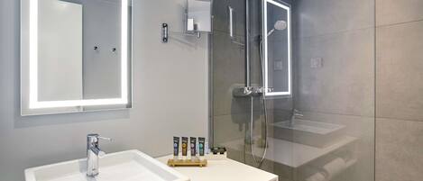 A modern bathroom with a white sink, a large mirror, and a glass-enclosed shower area.
