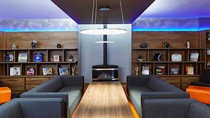 A modern lounge area with a central fireplace, wooden bookshelves, and comfortable seating. - Novotel London Waterloo (London)