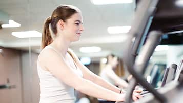 A gym with exercise equipment and a person using a treadmill.