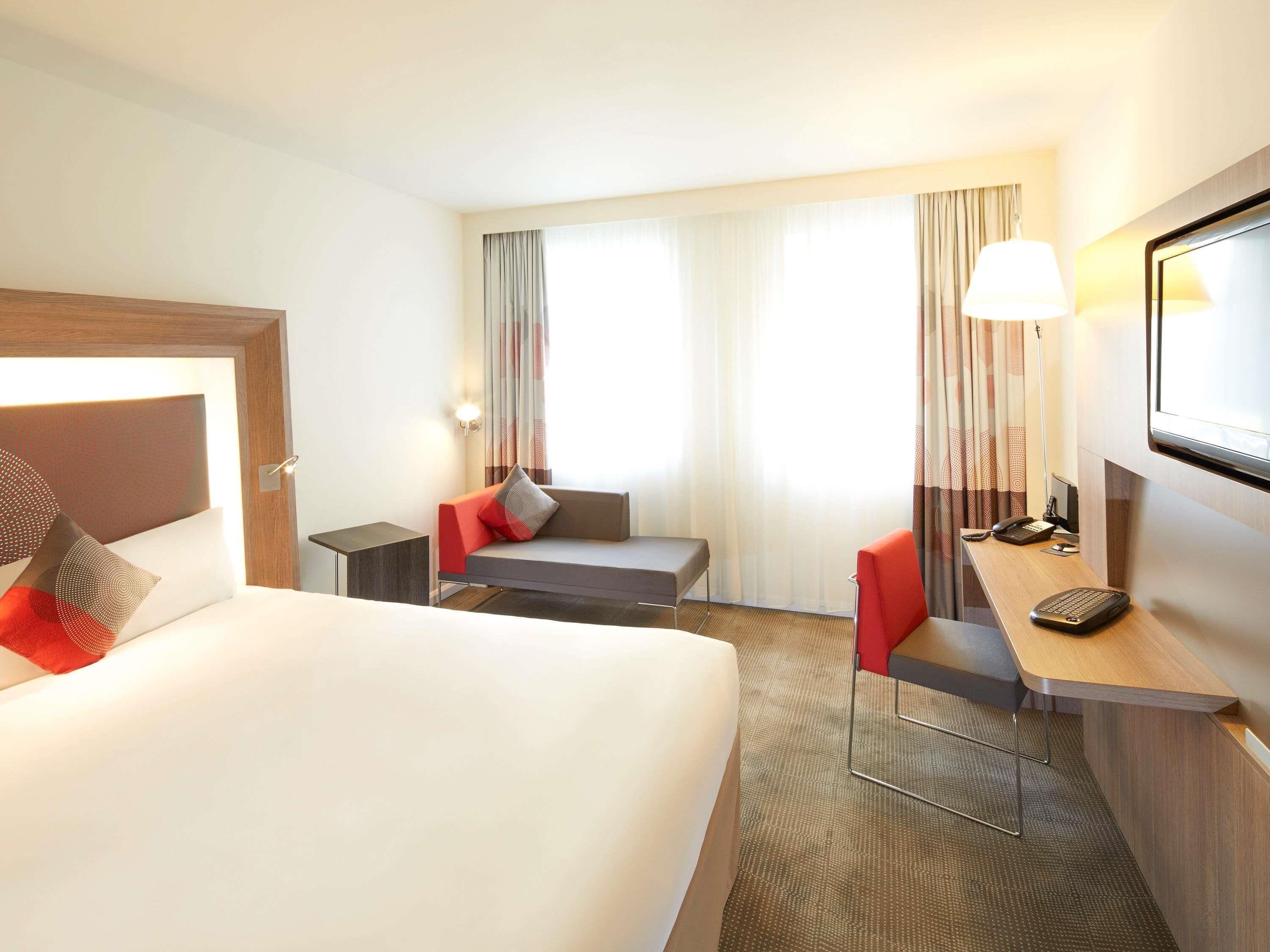 Una camera d'albergo con un letto, una scrivania con una sedia, un divano e una televisione.