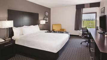 A modern hotel room with a large bed, a desk, a chair, a TV, and a view of a bridge.