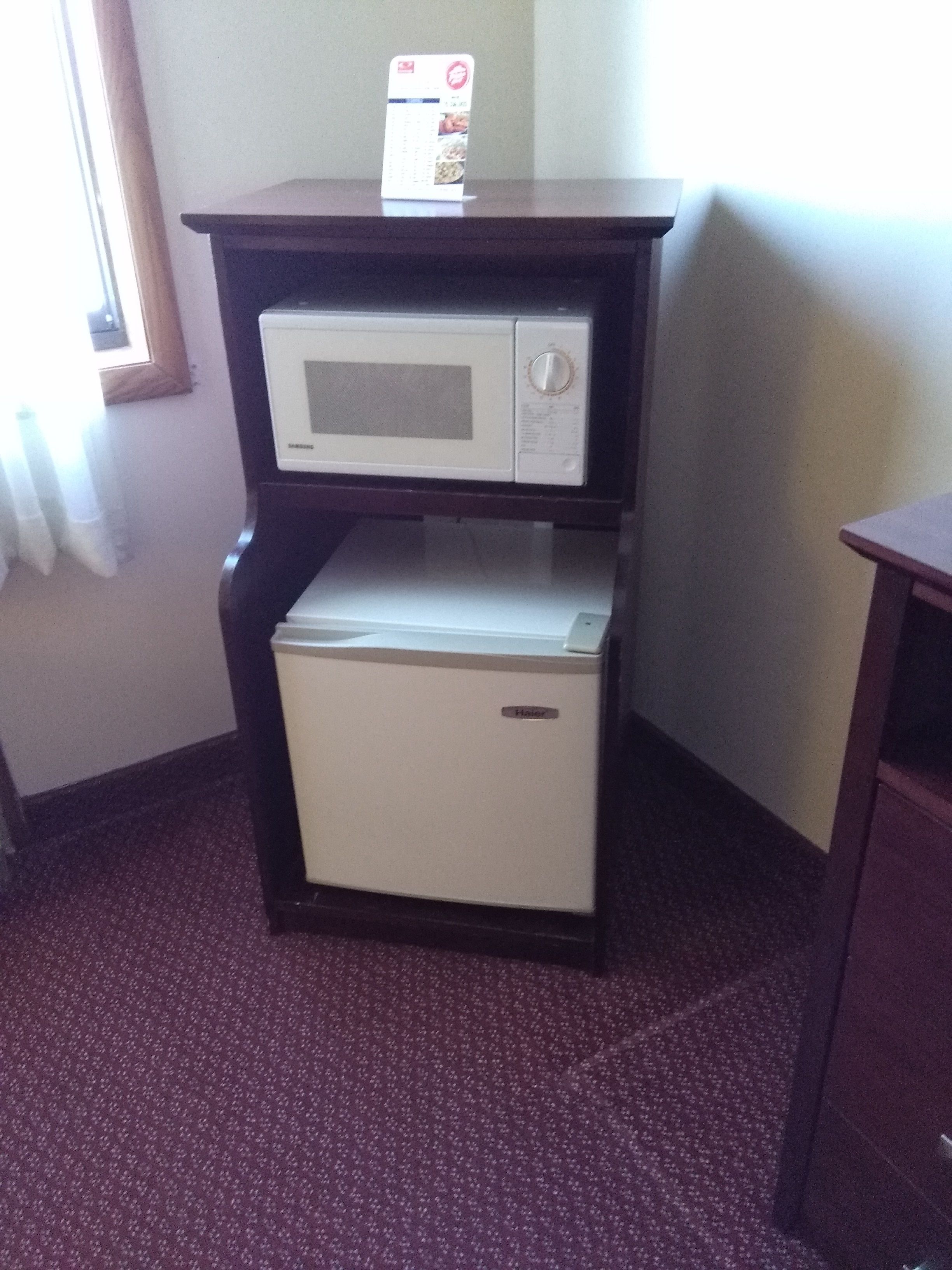 Una kitchenette compacta con microondas y refrigerador pequeño.