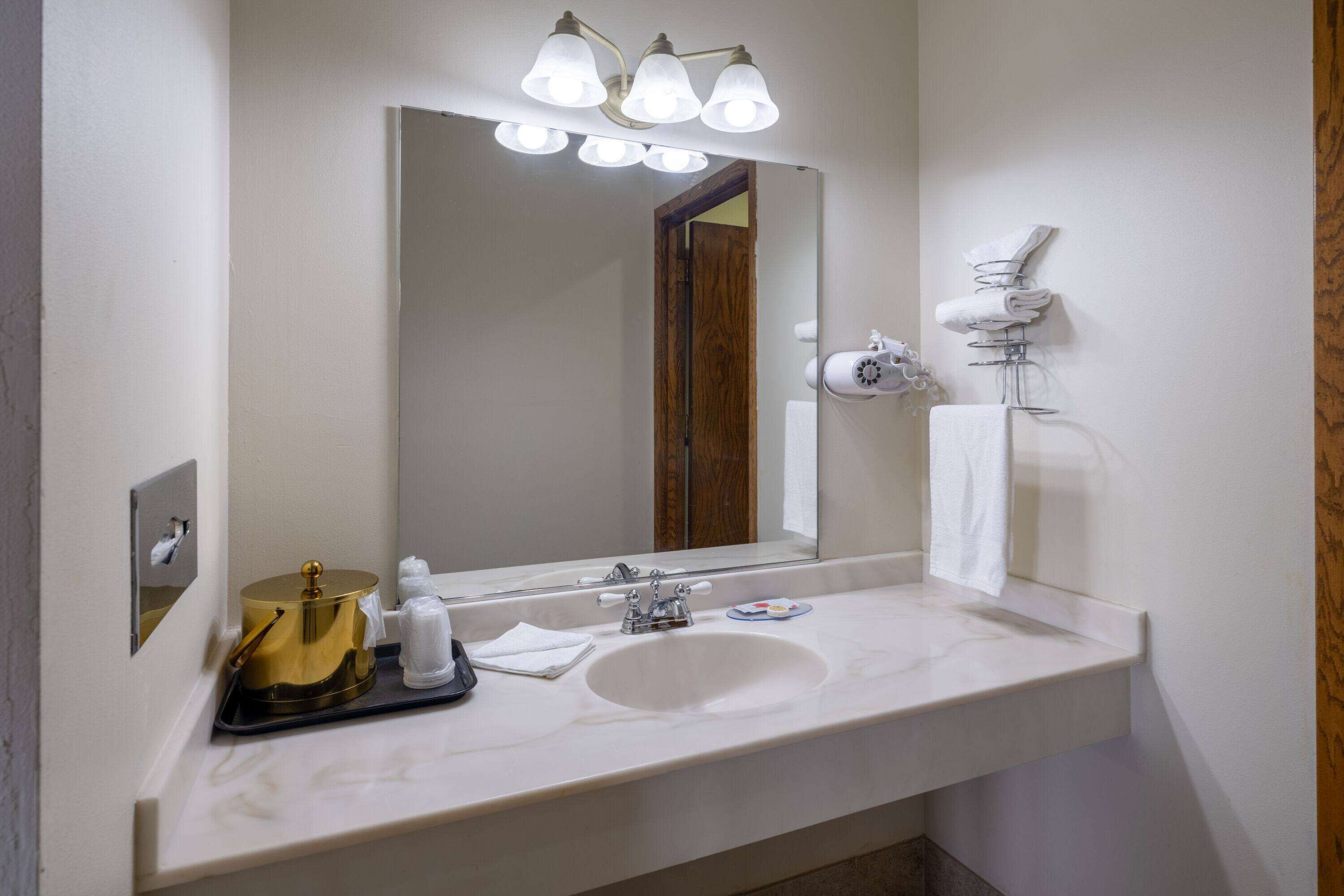 A hotel bathroom with a large mirror, a sink, and a towel rack.