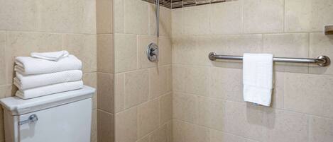Ein Badezimmer mit Toilette, Handtuchhalter und Duschbereich.