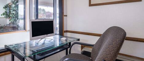 A modern office with a glass desk, a computer, and a patterned office chair.