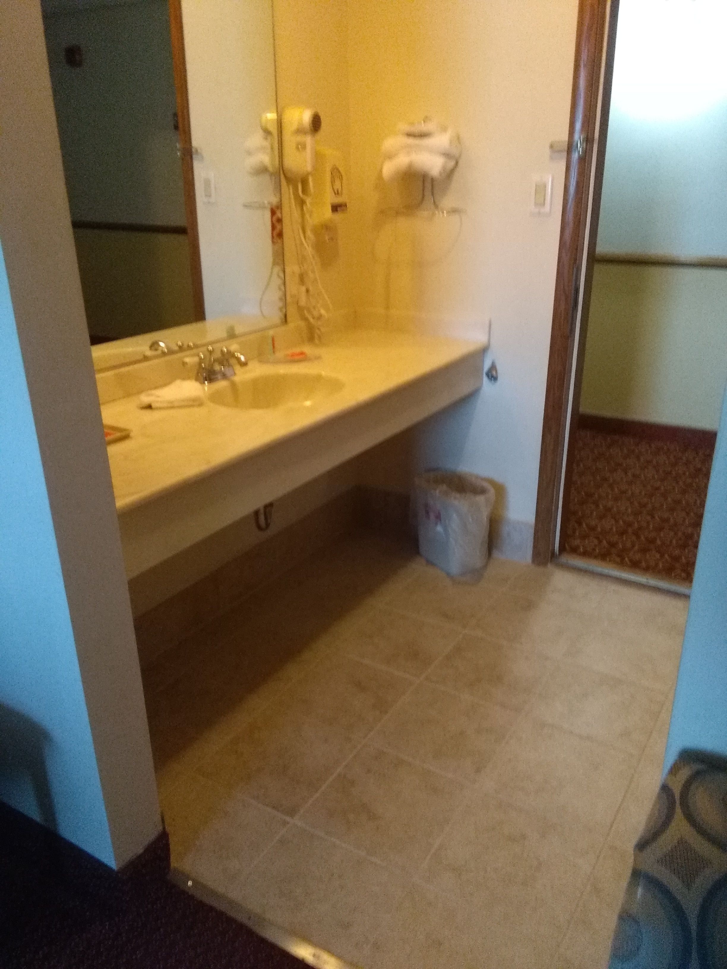 A bathroom with two sinks, a mirror, and a trash bin.