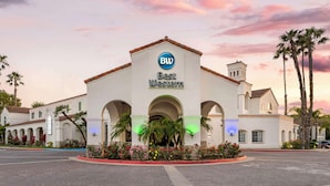 A hotel with a prominent 'BW Best Western' sign, featuring a classic Mediterranean architectural style with arched entrances and a tiled roof. - Best Western Posada Royale Hotel & Suites (Simi Valley)