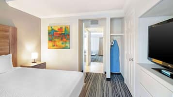 Habitació d'hotel amb un llit, una televisió, un quadre i una porta que dona a una altra estança.