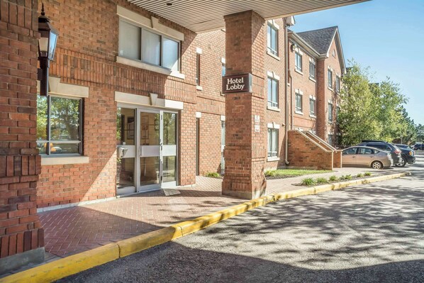 Enter the hotel lobby through the glass door, surrounded by a symmetrical brick facade and multiple windows.