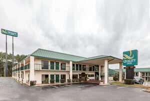 Un motel de dos pisos con techo verde y zona de estacionamiento cubierta.