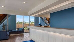 A modern reception area with a counter, seating, and a view of the outdoors.
