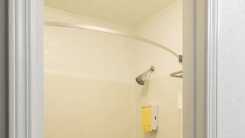 A bathroom with a bathtub, a toilet, and a shower head.