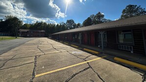 A motel with a row of cabins, a parking lot, and a clear sky with clouds. - American Inn Motel by Capital O Camden AL (Camden)