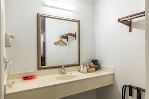 A bathroom with a sink, mirror, towel rack, and a coffee maker. - American Inn Motel by Capital O Camden AL (Camden)