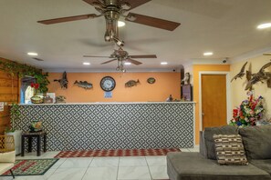 A living room with a ceiling fan, a clock, and decorative wall art including fish and a dinosaur.