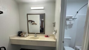 A bathroom with a white sink, a mirror, a hairdryer, and a toilet. - American Inn Motel by Capital O Camden AL (Camden)