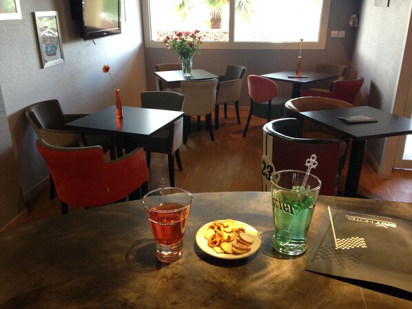 A restaurant interior with tables, chairs, and a window with a view of the outdoors. - Brit Hotel Les Evens (Saint-Saturnin)