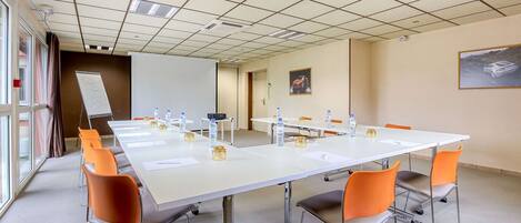 A conference room with a long table, chairs, water bottles, and a whiteboard.