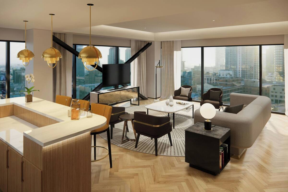 A modern living room with a large TV, comfortable seating, a kitchen area, and large windows offering a city view.
