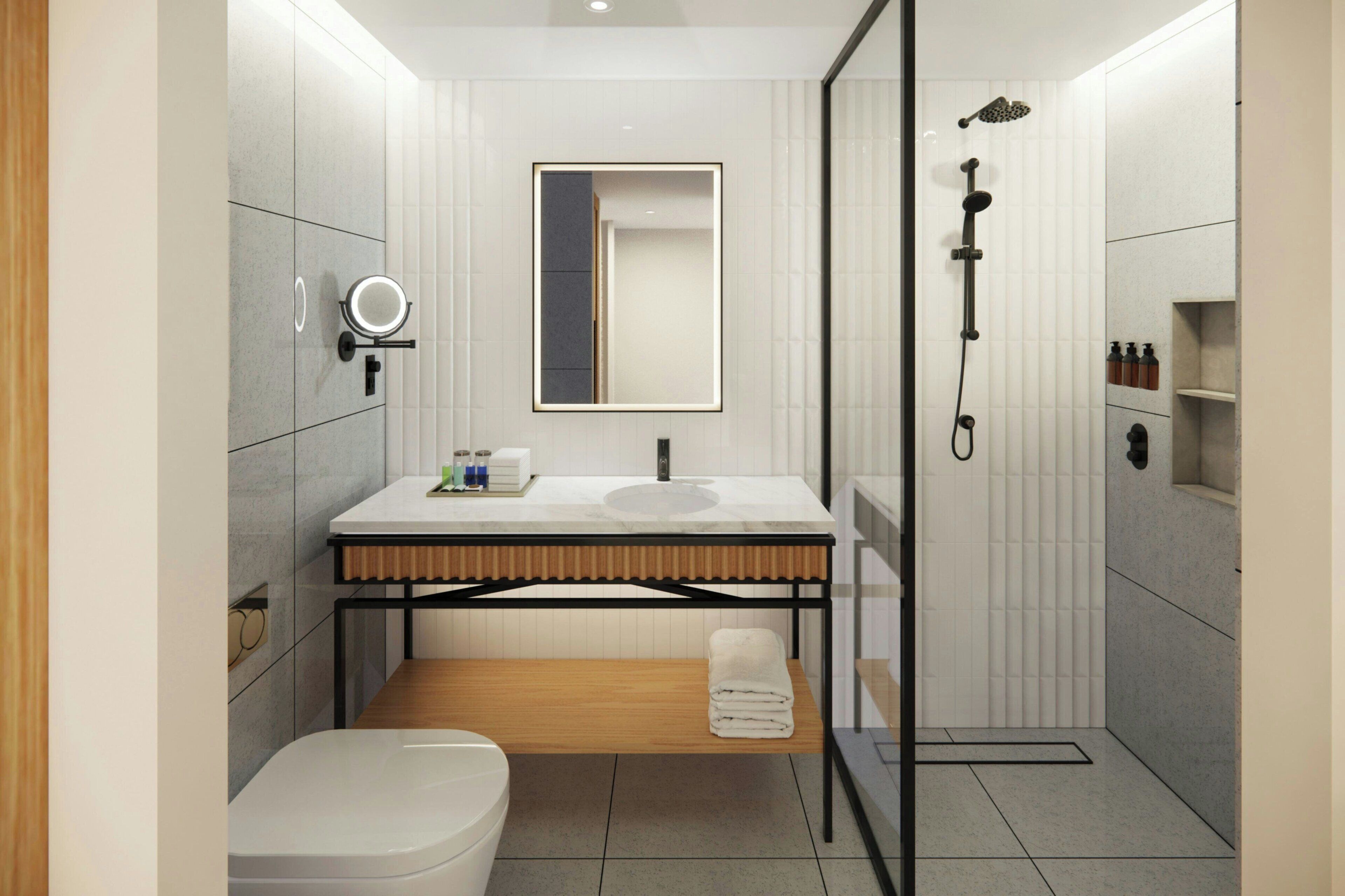 A modern bathroom with a toilet, sink, mirror, and shower.