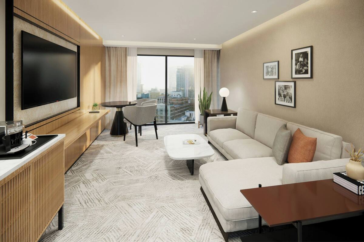 A modern living room with a large TV, a sofa, a coffee table, and a dining area with a table and chairs.