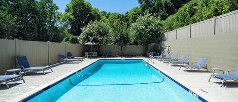 Una piscina rettangolare con indicazione della profondità di 3 piedi, circondata da lettini e da una recinzione, con alberi sullo sfondo.