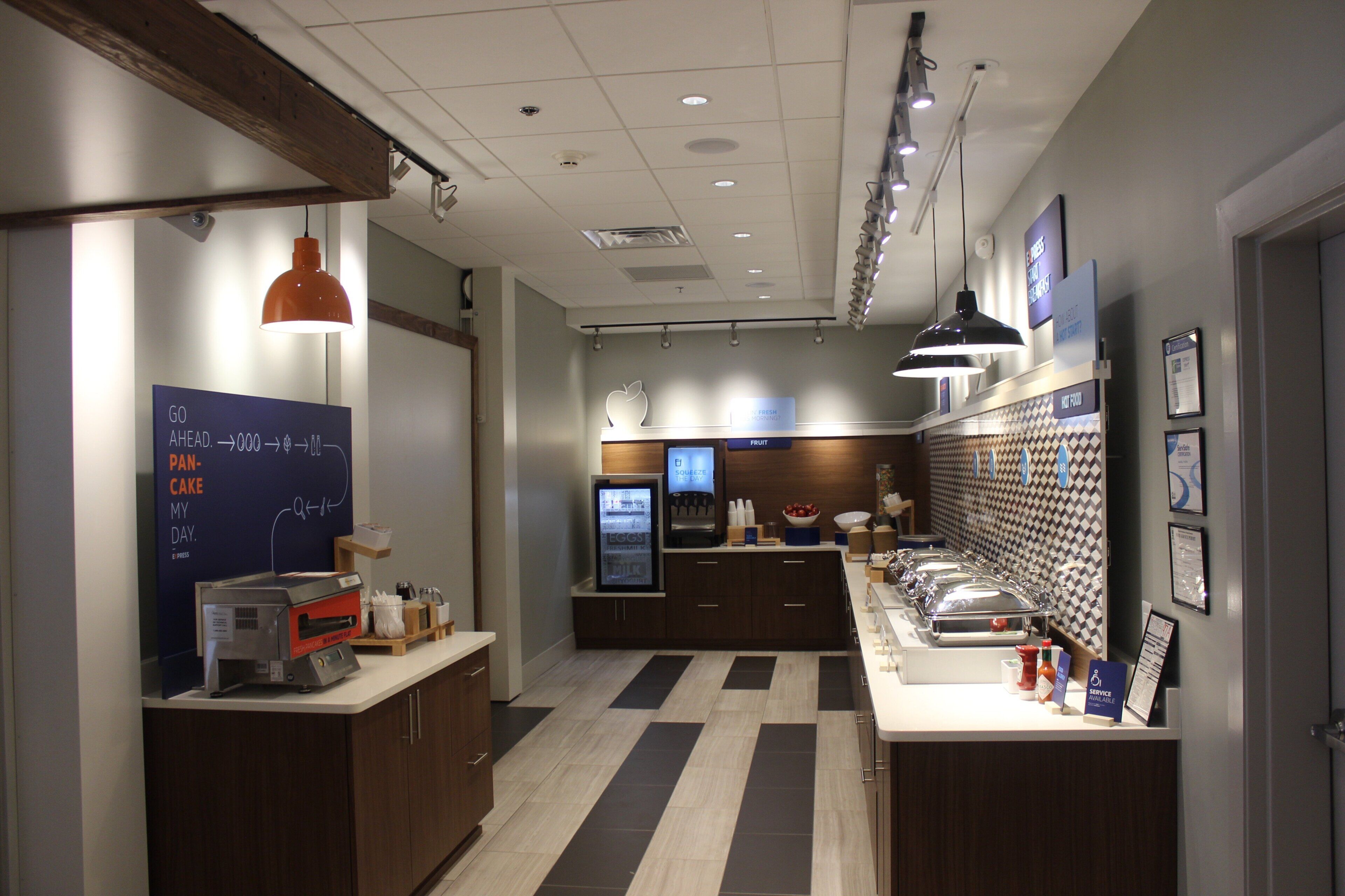A breakfast bar with a menu board, a coffee machine, and a fruit display.
