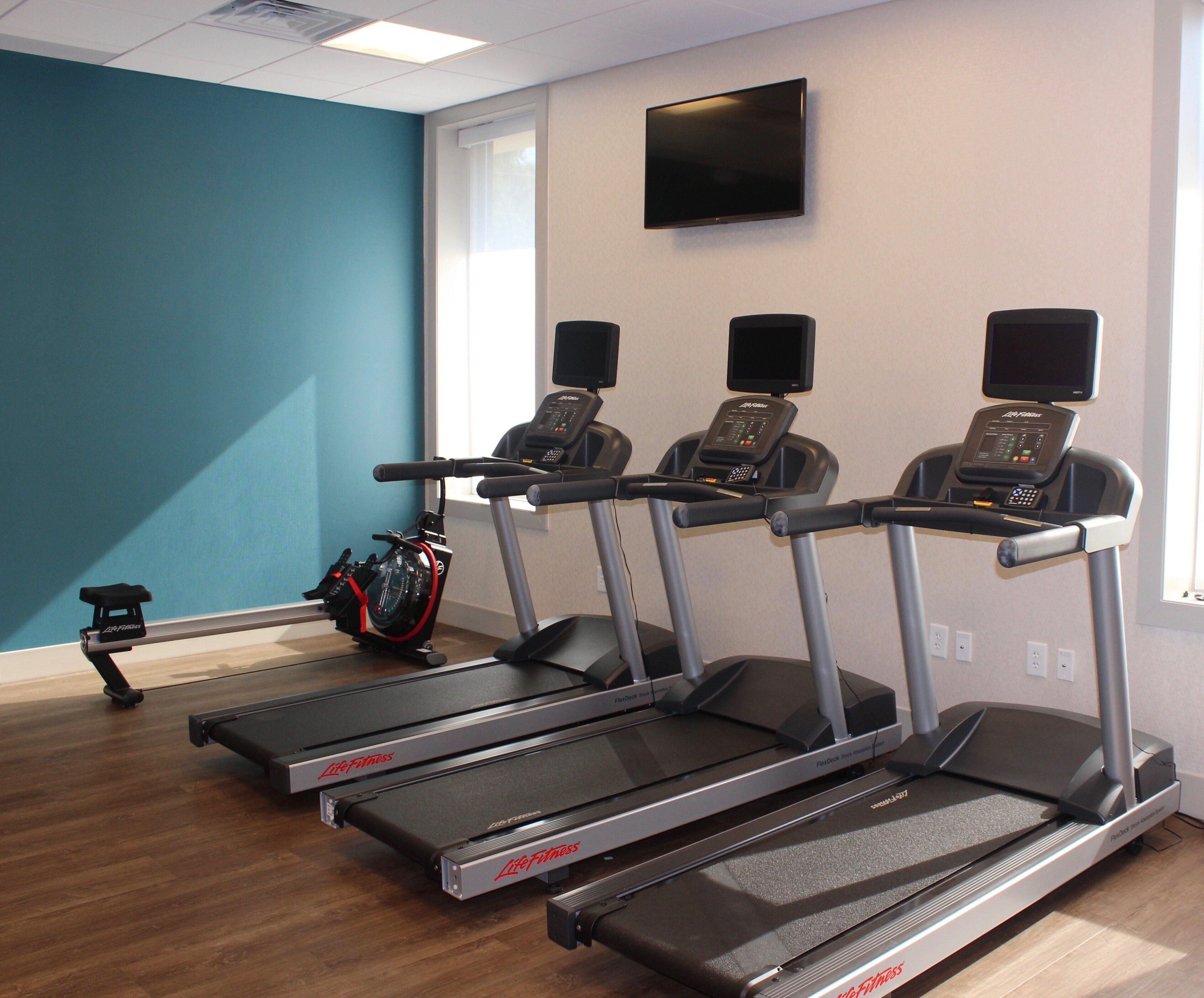 A fitness room with treadmills, a stationary bike, and a television on the wall.