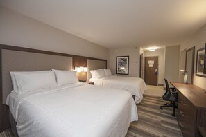 A hotel room with two beds, a desk, and a chair.