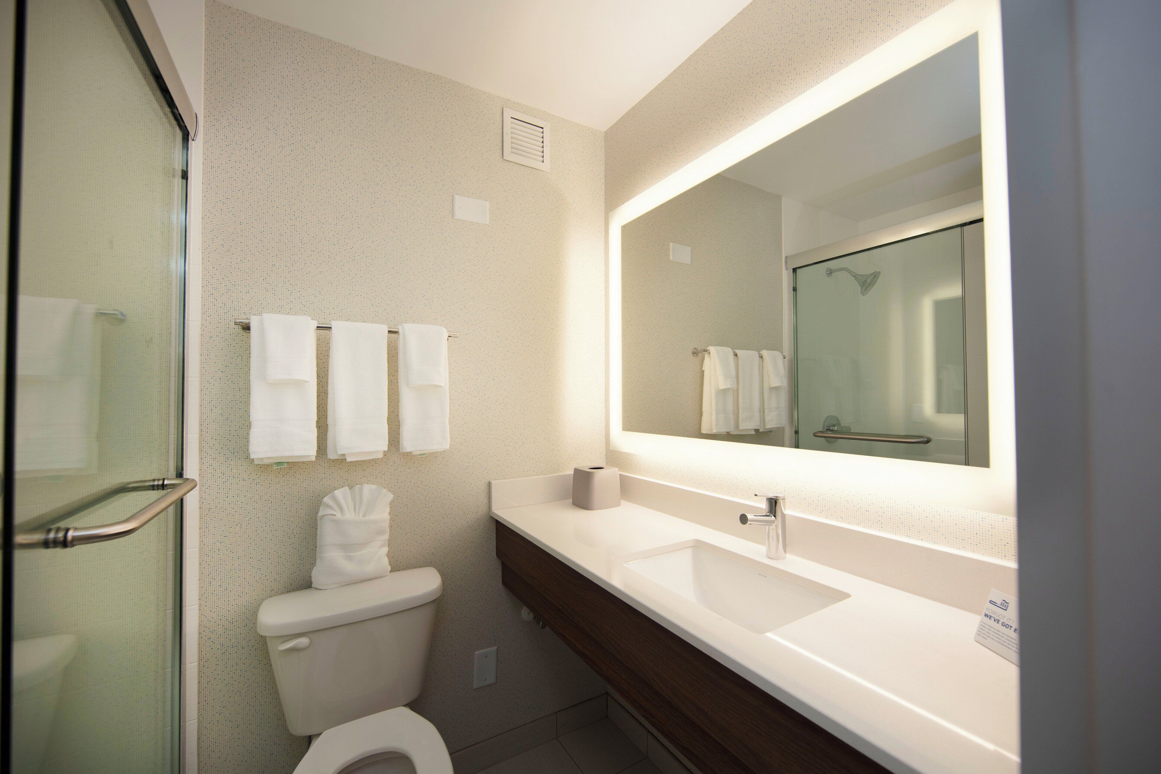 Un baño con cabina de ducha de vidrio, inodoro, lavabo y espejo.